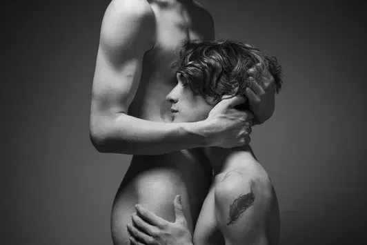 A soulful black and white photograph of one man leaning his head against another's chest, capturing a moment of deep trust and intimacy.